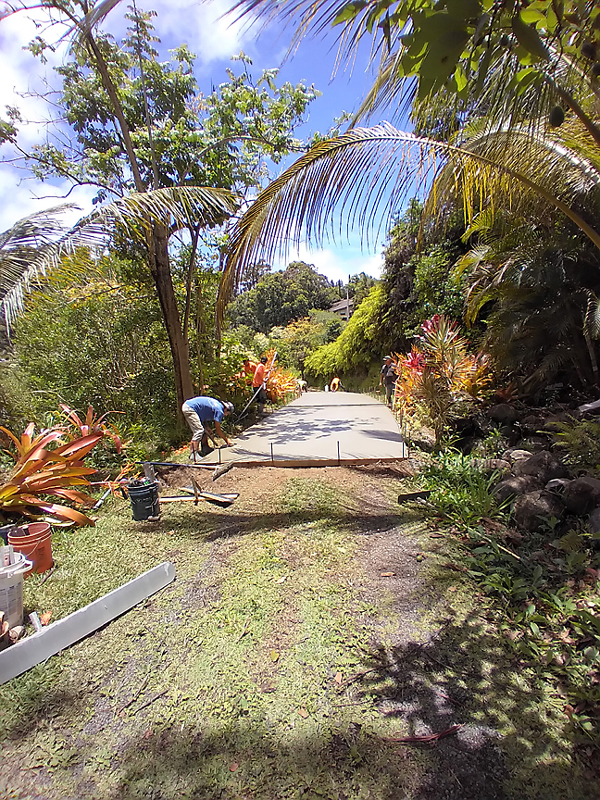 dirt driveway getting laid with concrete trees around and men working