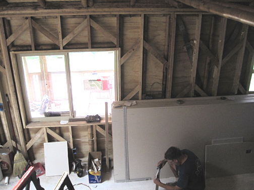 person sitting on floor working drywall by windows and wall